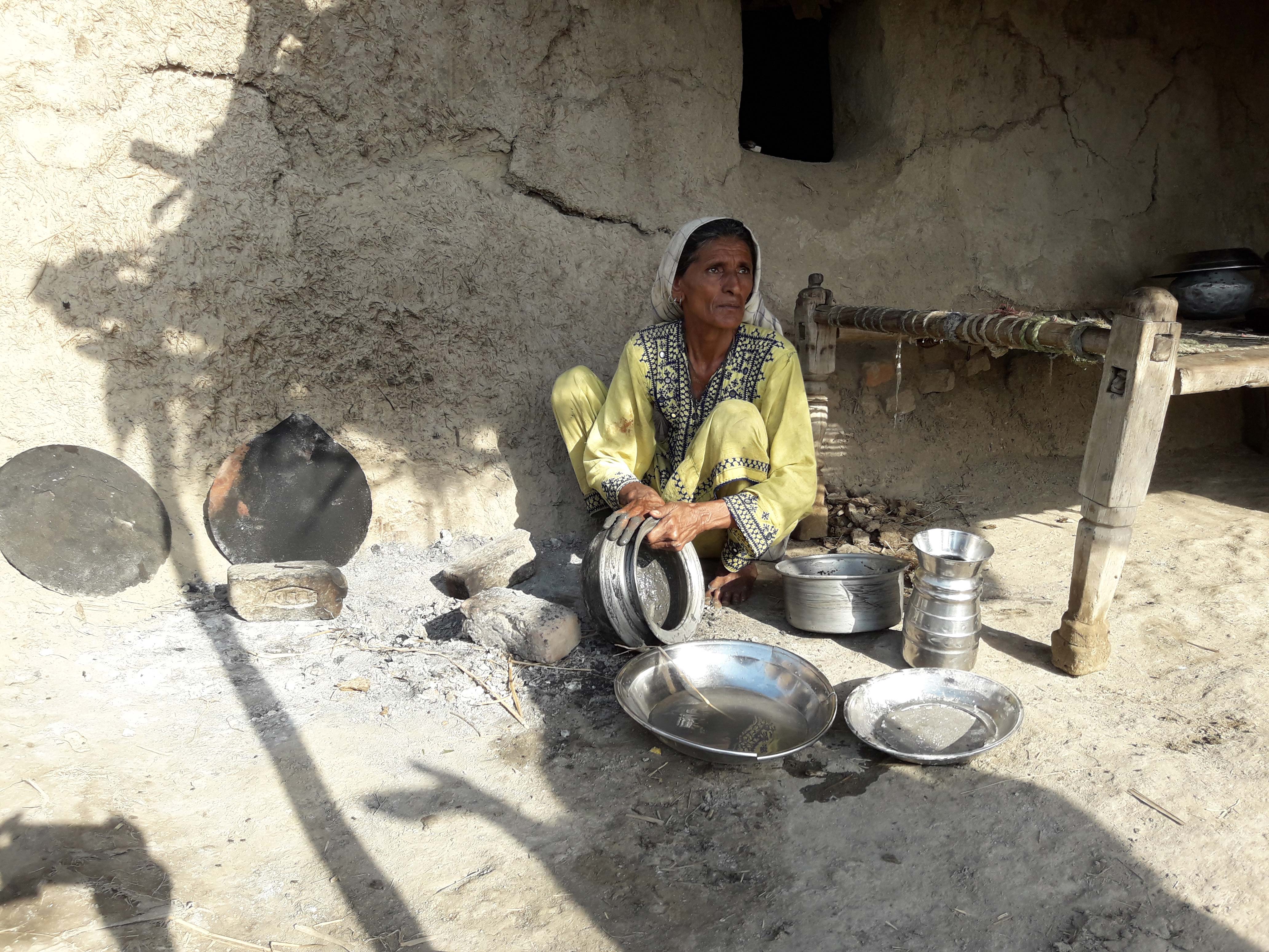 A woman washes dishes in a village near Larkana